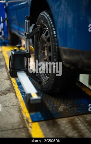 Close-up of a tire clamped by a leveler that passes the automatic alignment of the wheels in the garage, garage and tools for the mechanic. Stock Photo