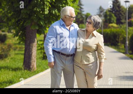 Portrait of a happy senior couple strolling in a green park on a sunny summer day Stock Photo