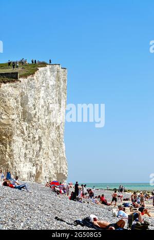 The unstable chalk cliffs at Birling Gap as viewed from the beach on a hot summers day with people on edge of cliff Eastbourne East Sussex England Stock Photo