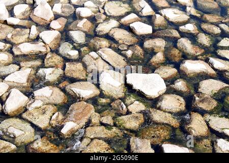 Pebbles submerged in water - Aerial view of stones in empty clear fresh water Stock Photo