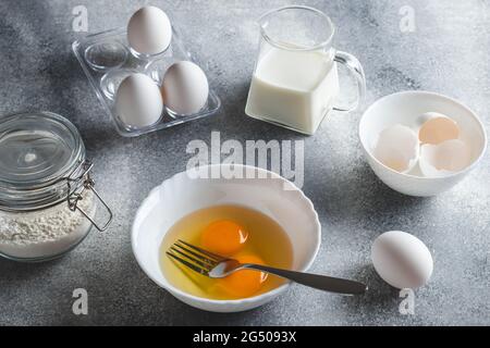 Raw ingredients for making an omelet. Eggs and flour on a gray background. Cooking concept Stock Photo