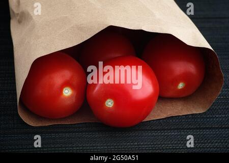Freshly harvested red tomatoes in a paper bag. Low key. Close-up. Stock Photo