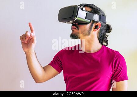 Young latin man using a Virtual Reality Device Glasses at home Stock Photo