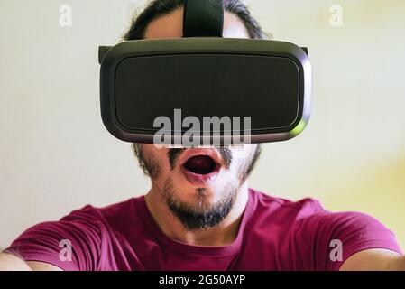Young latin man using a Virtual Reality Device Glasses at home Stock Photo