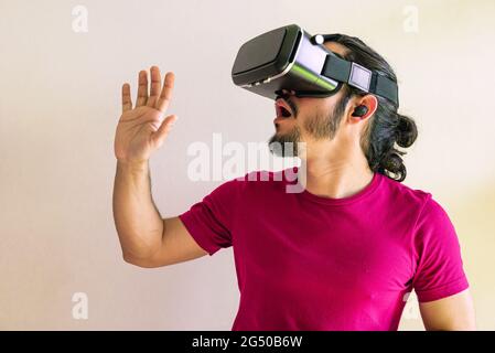 Young latin man using a Virtual Reality Device Glasses at home Stock Photo