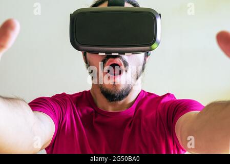 Young latin man using a Virtual Reality Device Glasses at home Stock Photo