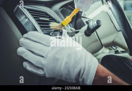 Caucasian Car Detailing Worker Cleaning Luxury Car Interior Using Brush. Automotive Theme. Stock Photo