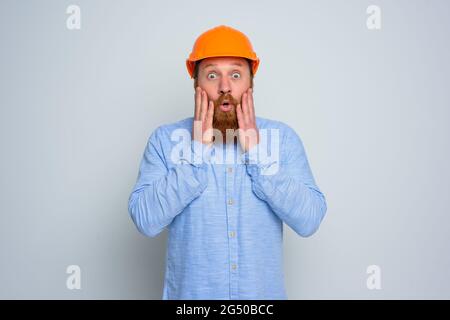 Isolated amazed architect with beard and orange helmet Stock Photo