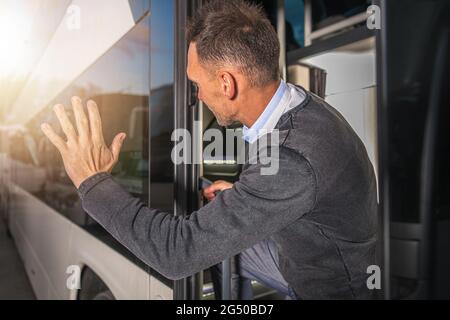 Elegant Caucasian Men Waving to Someone Leaving Bus Station in a Vehicle. Goodbye Hand Gesture. Business Travel Theme. Stock Photo