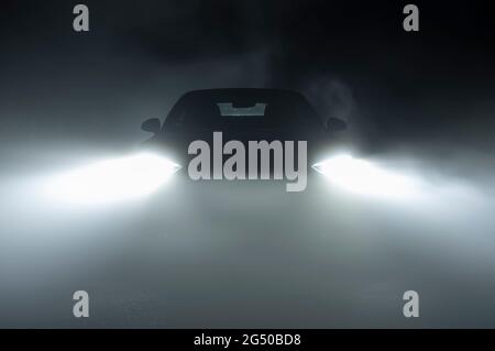 Modern LED Car Headlights in Dense Fog Automotive Industry Theme. Hard Road Driving Conditions. Stock Photo