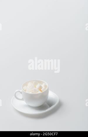 sugar cubes in cup with saucer on white Stock Photo