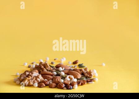 Close up of mixed seeds on a yellow background with some almonds and nuts. Stock Photo