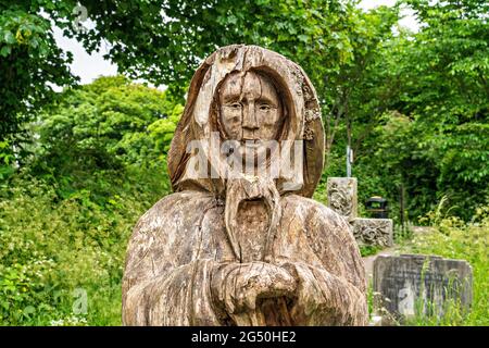 Chainsaw carving of Fisherman's wife (standing opposite her husband)  by Tim Burgess at Holy Trinity churchyard, Morecambe, Lancashire Stock Photo