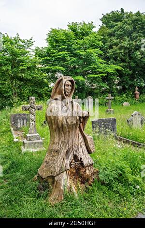 Chainsaw carving of Fisherman's wife (standing opposite her husband)  by Tim Burgess at Holy Trinity churchyard, Morecambe, Lancashire Stock Photo