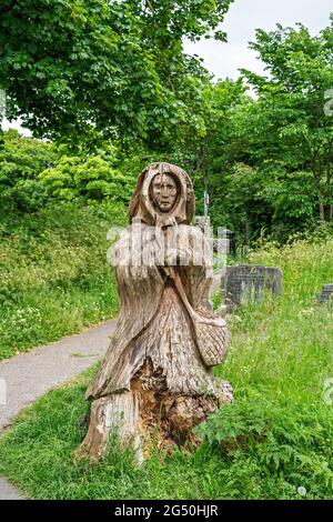 Chainsaw carving of Fisherman's wife (standing opposite her husband)  by Tim Burgess at Holy Trinity churchyard, Morecambe, Lancashire Stock Photo