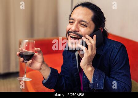 Young latin man drinking red wine at home in the living room Stock Photo