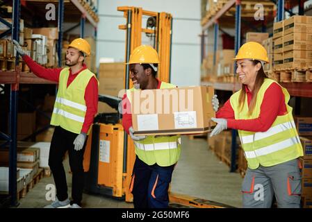 Positive diverse workers unloading boxes in warehouse Stock Photo