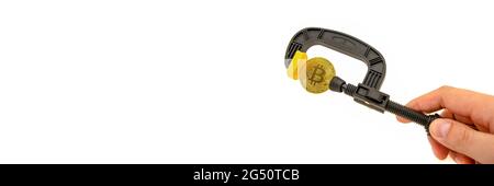 Pressure on bitcoin. Bitcoin is clamped in a vice on a white background. Prohibition of cryptocurrencies, rules, restrictions or security. Isolated. Stock Photo