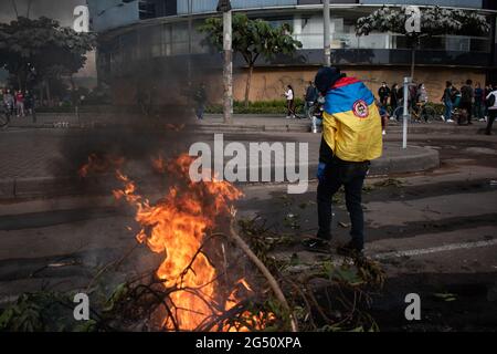 Bogota, Colombia. 23rd June, 2021. A demonstrator passes near to a fire barricade as demonstrations rise in northern Bogota, Colombia on june 22 after a demonstrator died in a police abuse of authority case during clashes with Colombia's riot police (ESMAD) on June 22, 2021. Credit: Long Visual Press/Alamy Live News Stock Photo