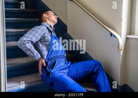 Worker Man Lying On Staircase After Slip And Fall Accident Stock Photo