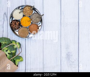 Flat lay of Indian spices with a bag of broccoli and room for copy. Stock Photo