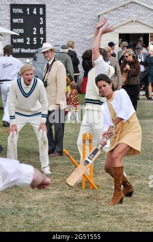 Amanda Stretton, female motorsport and motor industry TV presenter, playing cricket for the cameras at the Goodwood Revival 2012, UK. Presenting Stock Photo