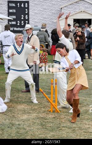 Amanda Stretton, female motorsport and motor industry TV presenter, playing cricket for the cameras at the Goodwood Revival 2012, UK. Presenting Stock Photo