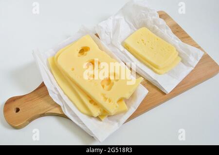 slices of Emmental cheese and Tilsit cheese on cutting board, close up, isolated on white background Stock Photo