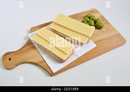 two cheese sandwiches with green olives on cutting board, close up, isolated on white background Stock Photo