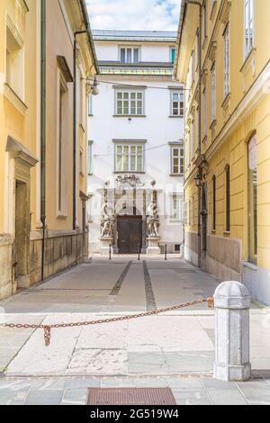 Ljubljana, Slovenia - August 15, 2018: A rich-decorated door with sculptures at the end of a small pedestrian alley in downtown Stock Photo