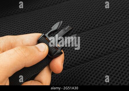 A semi-automatic fastener of the travel backpack on the man hand close-up, black belts nylon background photo Stock Photo