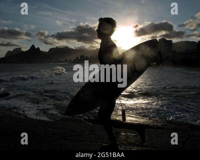 The silhouette of a surfer running to the water in Arpoador, a rock between the Ipanema and Copacabana beaches. Rio de Janeiro, Brazil Stock Photo