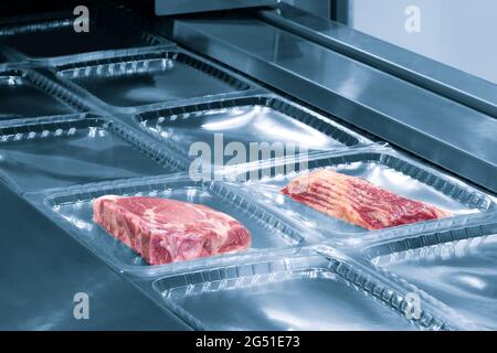 Linear food plastic tray package heat sealing machine. Food industry concept background Stock Photo