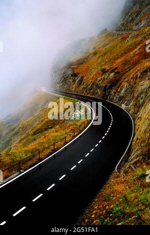 Road on mountainside disappearing into fog, Switzerland Stock Photo