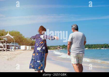 Older Couple Walking Together On A Beach Stock Photo