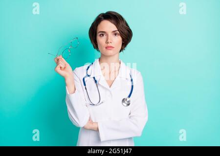 Photo portrait of serious nurse wearing white uniform keeping glasses isolated bright teal color background Stock Photo