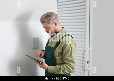 Worker with tablet computer checking alarm system indoors Stock Photo