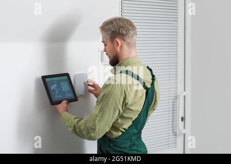 Worker with tablet computer checking alarm system indoors Stock Photo
