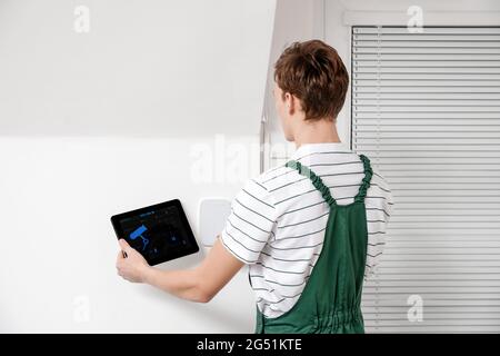 Worker with tablet computer checking alarm system indoors Stock Photo