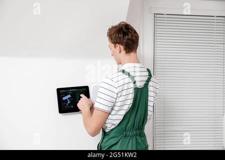 Worker with tablet computer checking alarm system indoors Stock Photo