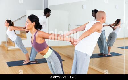 Couples practicing yoga with partner at studio Stock Photo