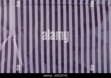 Plastic wrap texture with vertical lines. Plastic texture of a piece of crumpled pink striped bright cellophane. Top view Stock Photo