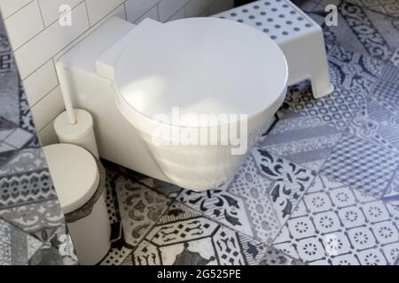 Stylish home interior design of restroom with white toilet bowl and accessories on ornamental tile floor Stock Photo