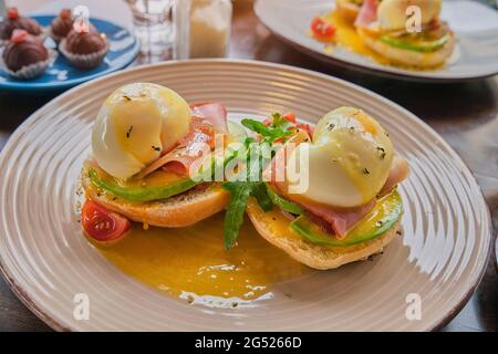 Eggs Benedict on toasted muffins with ham, poached egg and hollandaise . Stock Photo