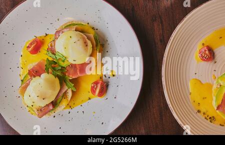 Eggs Benedict on toasted muffins with ham, poached egg and hollandaise . Stock Photo