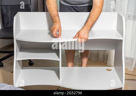 master assembles a new shelf at home Stock Photo