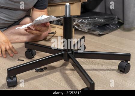 man assembles a chair according to instructions Stock Photo