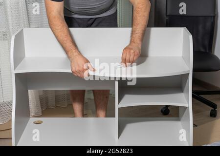 a man assembles a new shelf at home. Stock Photo