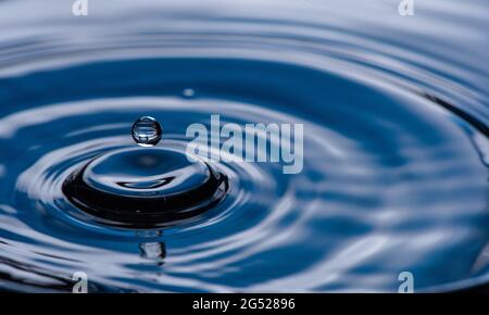 Water drop splash on blue colored. Stock Photo