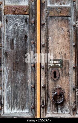 A warning sign on the very old and repeatedly repaired wooden east door of the Parish Church of St Clement, Bridge St, Cambridge, UK Stock Photo